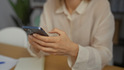 Woman using smartphone in modern office room showcasing technology productivity and business...