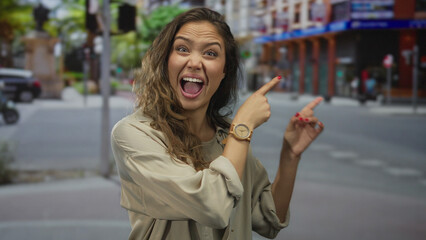 Fototapeta premium Woman pointing enthusiastically in vibrant urban street setting, showcasing expressive emotions and casual style with bustling city backdrop hinting at dynamic outdoor environment.