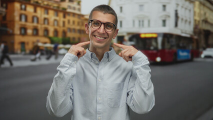 Man smiling with glasses on urban street pointing at smile with fingers in city background outdoor...