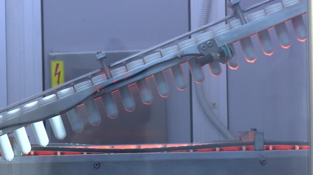 A pile of preforms for making plastic bottles. Blank for the production of containers. Conveyor belt deliver the preform shape to the  blow mold machine.The operation of plastic bottle blowing machine