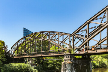 Obraz premium View of the railway bridge in Frankfurt, Germany, from the Main River A high-rise building and blue sky are visible in the background.