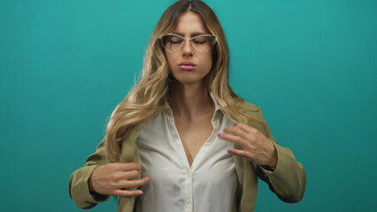 Business woman adjusts tailored sleek blazer in a turquoise studio; confidence poise elegance...