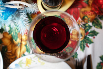 calice riempito parzialmente con del vino rosso, visto da sopra, su un tavolo apparecchiato in tema natalizio
