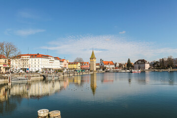 Obraz premium A Lindau city on Bodensee in Bayern Germanywith a large tower in the middle of it the panorama of the building is reflected in the calm water.