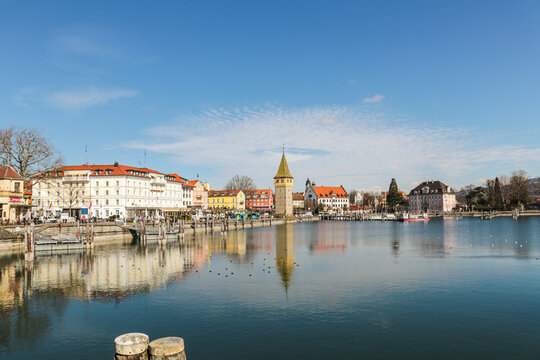 A Lindau city on Bodensee in Bayern Germanywith a large tower in the middle of it the panorama of the building is reflected in the calm water.