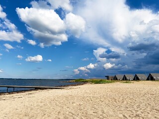 Beautiful calm landscape, seascape, camping, sunny beach, pier, dramatic cloudy blue sky.