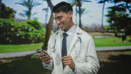 Man doctor with stethoscope in white coat taps smartphone screen in lush green forest clearing;...