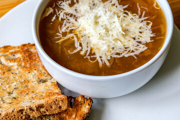 A Bowl Of Traditional French Onion Soup Topped With Grated Cheese And Toasted Bread