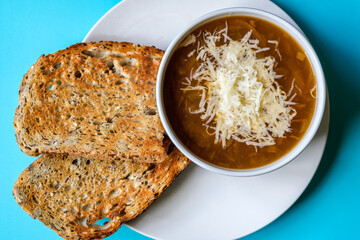 A Bowl Of Traditional French Onion Soup Topped With Grated Cheese And Toasted Bread
