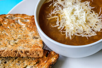 A Bowl Of Traditional French Onion Soup Topped With Grated Cheese And Toasted Bread