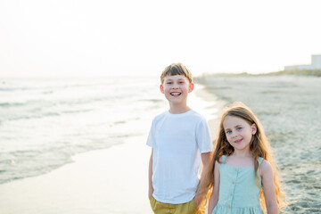Little boy and girl near the sea at sunset. Children on the beach. Sea vacation.
