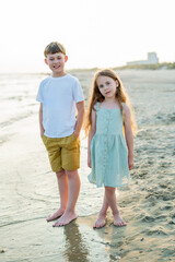 Little boy and girl near the sea at sunset. Children on the beach. Sea vacation.