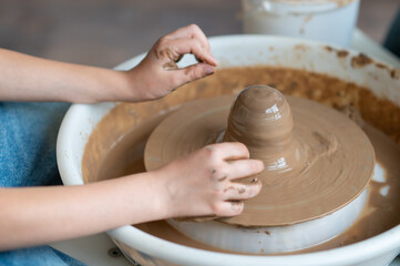 Close-up hands of boy shaping clay on a pottery wheel