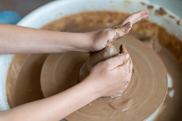 Close-up hands of boy shaping clay on a pottery wheel