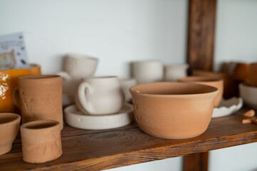 Ceramic pottery on wooden shelf in cozy workshop