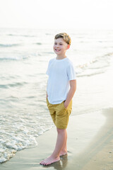 Portrait of a smiling boy of 10 years old near the sea at sunset. Child on the beach. Vacation.