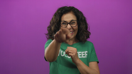 Woman volunteer in green uniform happily clapping with a joyful expression against an isolated pink background