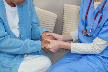 Physiotherapist warmly clasps elderly patient’s hands, providing reassurance and emotional...