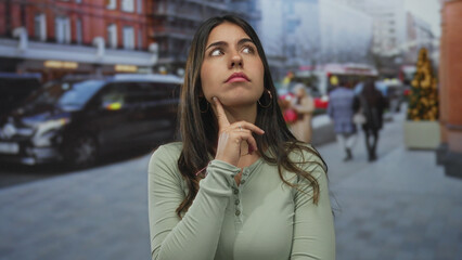 Obraz premium Woman contemplating while standing on a busy city street surrounded by buildings and vehicles, indicating an outdoor urban setting filled with pedestrians.