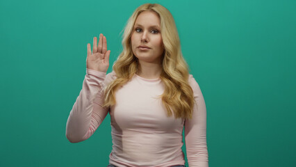 Woman raising hand for oath close-up against green backdrop wearing pink shirt portraying...