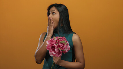 Woman yawning holding flowers against an orange background, expressing tiredness.