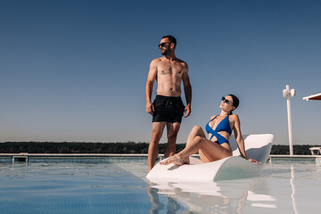 Beautiful young couple enjoying vacation and relaxing together in the pool. Concept vacation,...