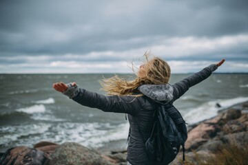 Embracing nature on a rocky beach during a breezy day