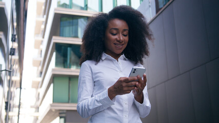 Successful African American woman businesswoman girl going walking downtown user mobile phone...