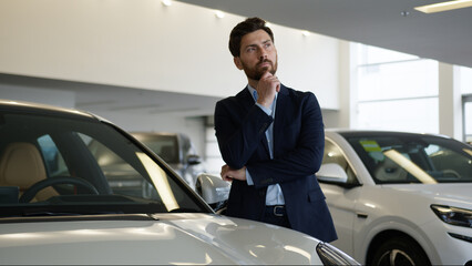 Thoughtful pensive Caucasian man client consumer new car choosing thinking decide purchase auto...
