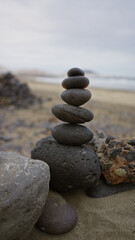 Stacked black rocks on a sandy famara beach in lanzarote, canary islands, during daylight, showcasing serenity in an outdoor coastal setting.