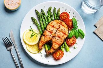 Grilled salmon steak with green asparagus, tomatoes and lemon slices