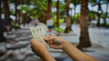 Man holding uae dirham banknotes on a city street, showcasing the currency in an outdoor urban...
