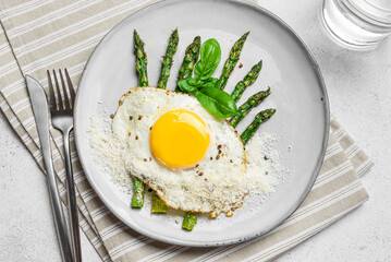 Fried egg with green asparagus and grated parmesan cheese, healthy breakfast