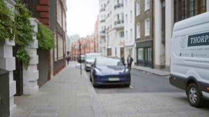 Blurred urban street scene in london showcases defocused cars and pedestrians against a backdrop of historic buildings, capturing an essence of winter in the uk.