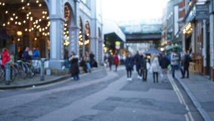 Blurred winter scene on london street with people walking among festive christmas decorations and bokeh lights creating a cozy atmosphere.