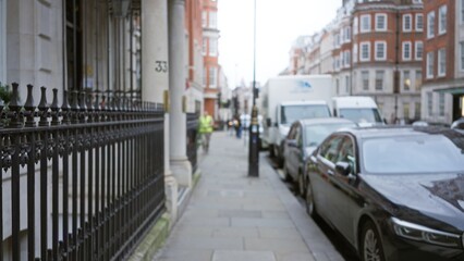 Blurred london street scene in winter, showcasing parked cars, historic buildings, and people walking, capturing the essence of urban life with a soft defocused effect.