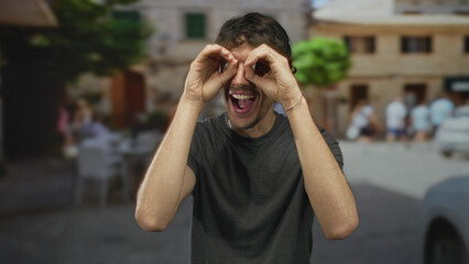 Fototapeta premium Man gestures with open arms and excited grin on street with blurred historic building behind; excitement.