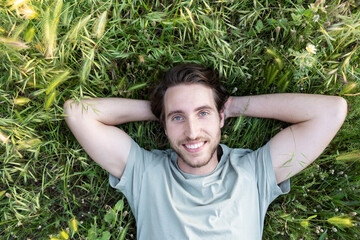 Portrait of a relaxed man lying on green grass seen from above