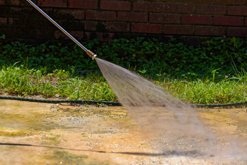 Cleaning concrete in the garden with a pressure washer