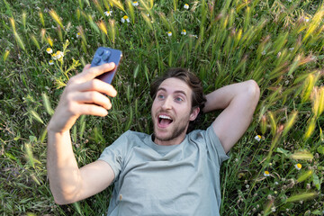 Young man lying on the grass making a video call