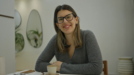 Woman sipping coffee in a modern luxury restaurant with stylish decor and bright lighting,...