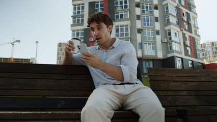Caucasian man businessman city urban drinking coffee read news amazed male shocked mobile phone...