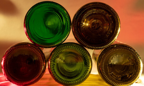 botellas de vino bac&iacute;as de color verde marr&oacute;n rojo y amarillo de pie una al lado de la otra enfocando la culo de las botellas