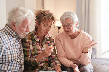 Smiling Senior couple and Caregiver Sharing a Moment sitting together on sofa at home. Concept of...