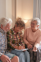 Smiling Senior couple and Caregiver Sharing a Moment sitting together on sofa at home. Concept of...