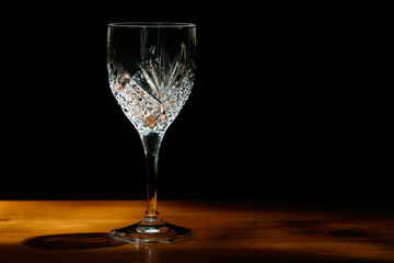 An empty crystal glass standing on a wooden table.