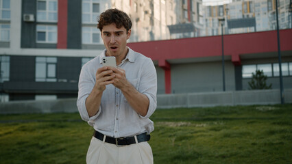 Caucasian man holding mobile phone smartphone failure male bankrupt guy businessman emotional shock...