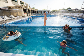 Family enjoying time together in an outdoor swimming pool on a sunny day
