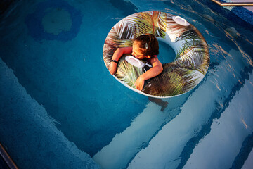 Child relaxing in a pool using an inflatable tube on a sunny day