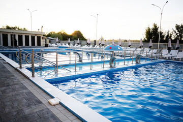 Modern outdoor swimming pool with clean water and surrounding relaxation area at sunset